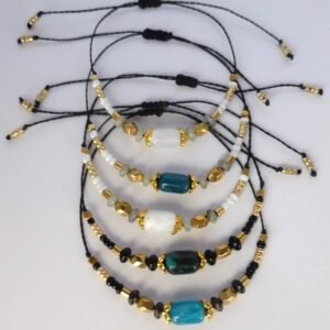 Bracelet Lindo avec perles en pierre naturelle gemme, perles en hématite doré et perles de rocaille noire. Les perles sont montées sur un cordon ciré terminé par des perles de rocaille dorées.