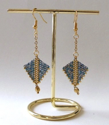 Boucles d'oreilles Arrowa en perles miyuki tissées à la main. Couleurs gris-bleu et dorée. Crochet en acier inoxydable couleur charbon. Modèle gris-bleu et doré. Vue sur portant.