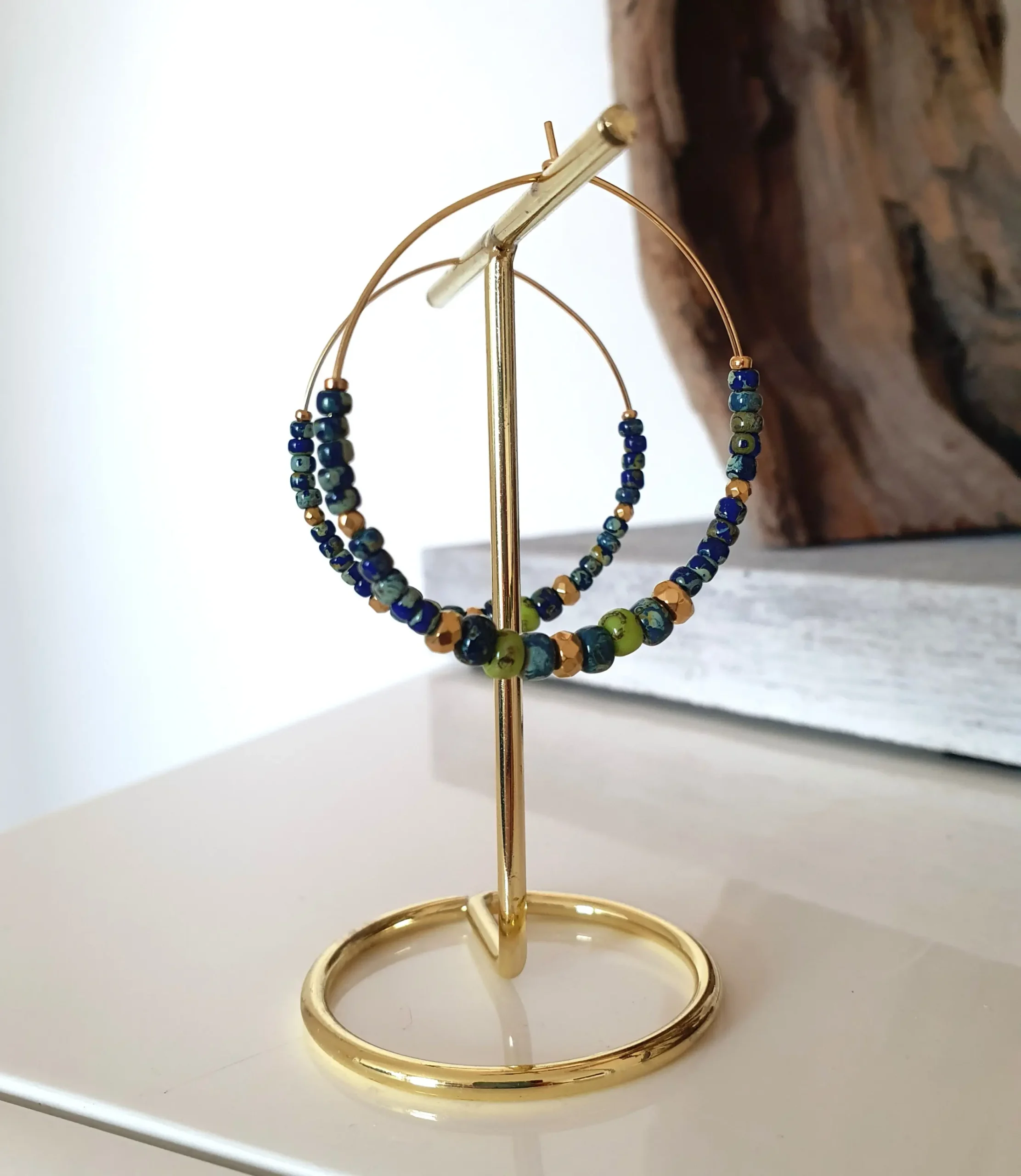 Boucles d'oreilles créoles en perles bleues et vertes anis picasso. Vue sur portant.