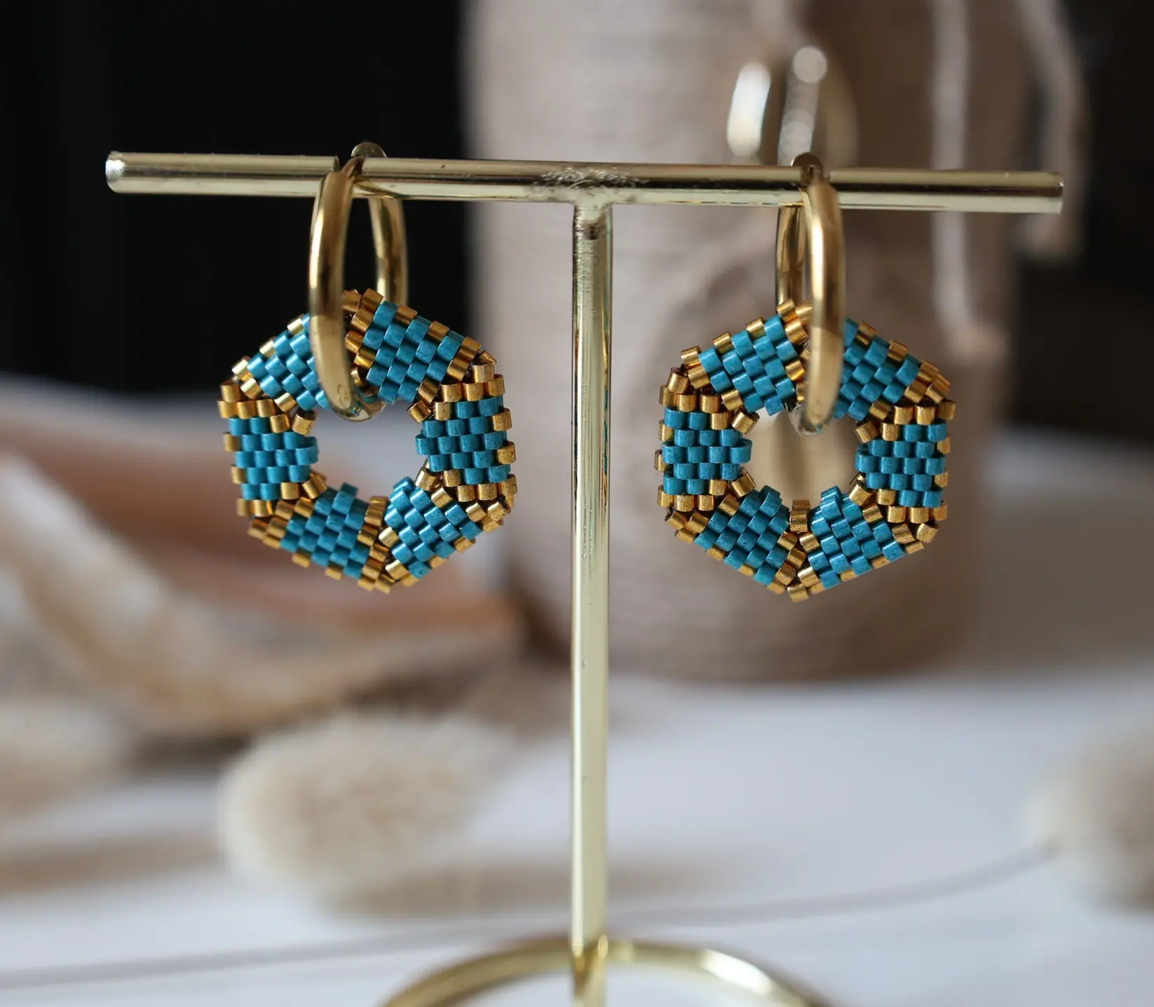 Boucles d'oreilles créoles avec pampille hexagonale en perles miyuki tissées bleues et dorées. Vue sur portant