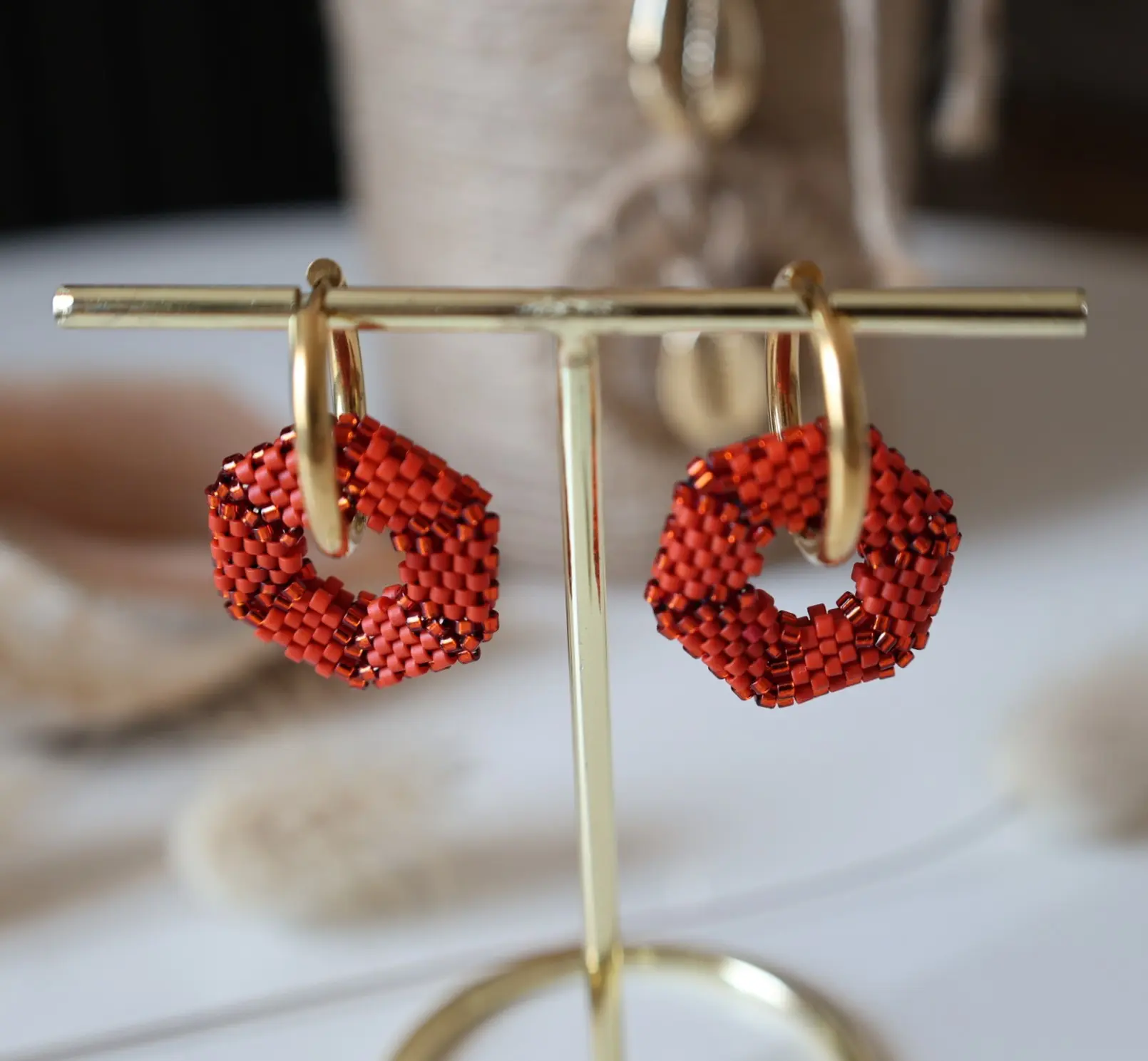 Boucles d'oreilles créoles avec pampille hexagonale en perles miyuki tissées rouges. Vue sur portant