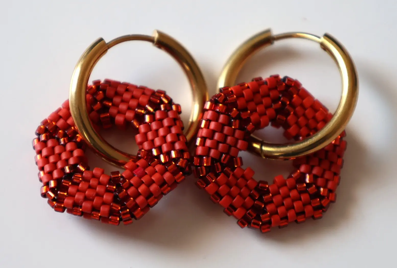 Boucles d'oreilles créoles avec pampille hexagonale en perles miyuki tissées rouges. Vue à plat