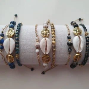 Bracelet Trio Ocealis avec coquillage cauri et perles de pierre naturelle. Ensemble. Vue sur coussin