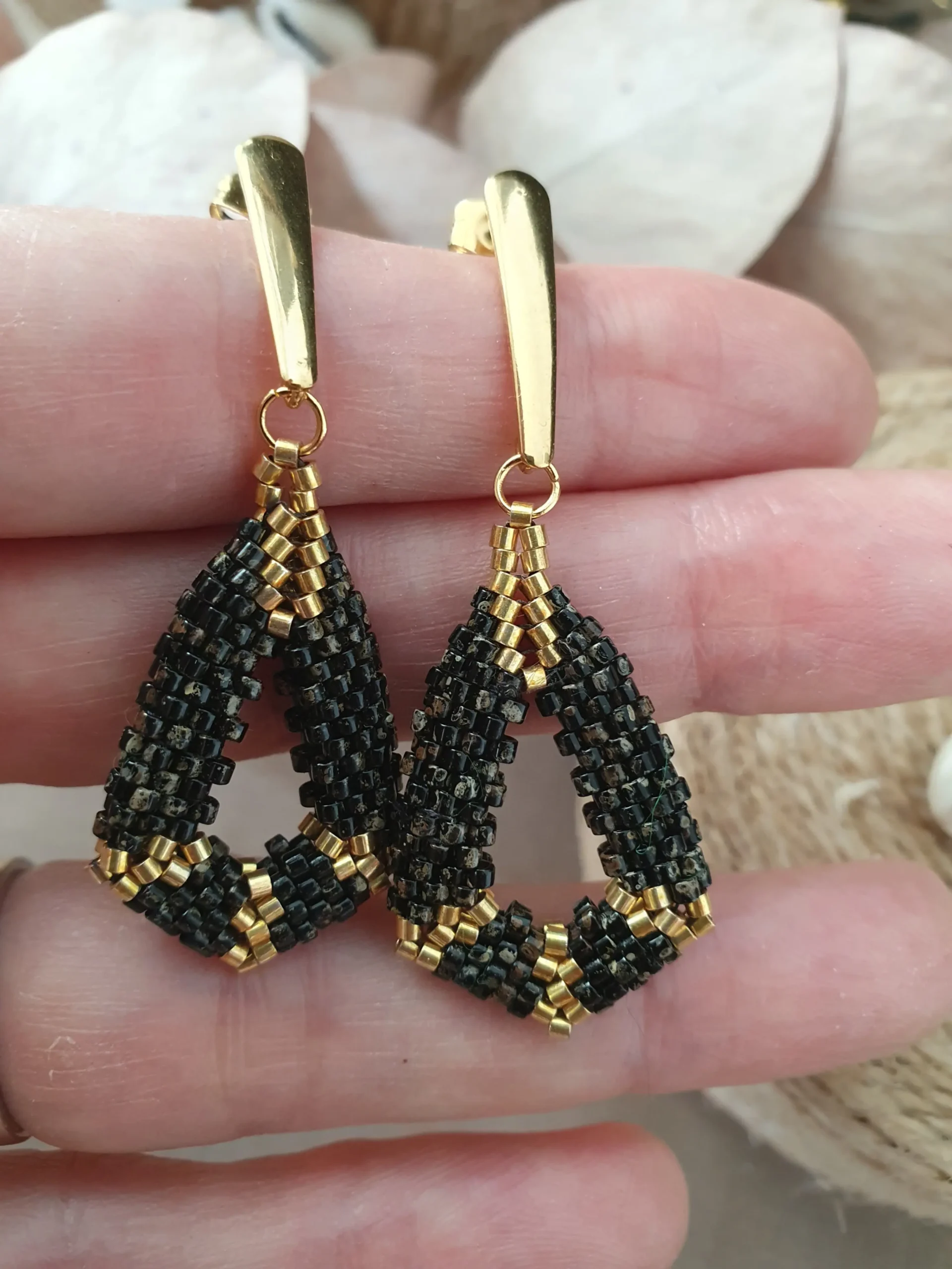 boucles d'oreilles pendantes en perles tissées noir picasso et doré. collection kimi. Vue dans la main.