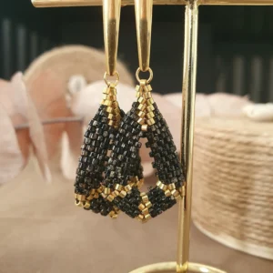 boucles d'oreilles pendantes en perles tissées noir picasso et doré. collection kimi. Vue sur portant